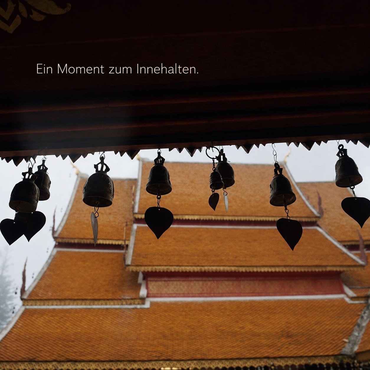 Tempelglocken vor einem thailändischen Tempeldach