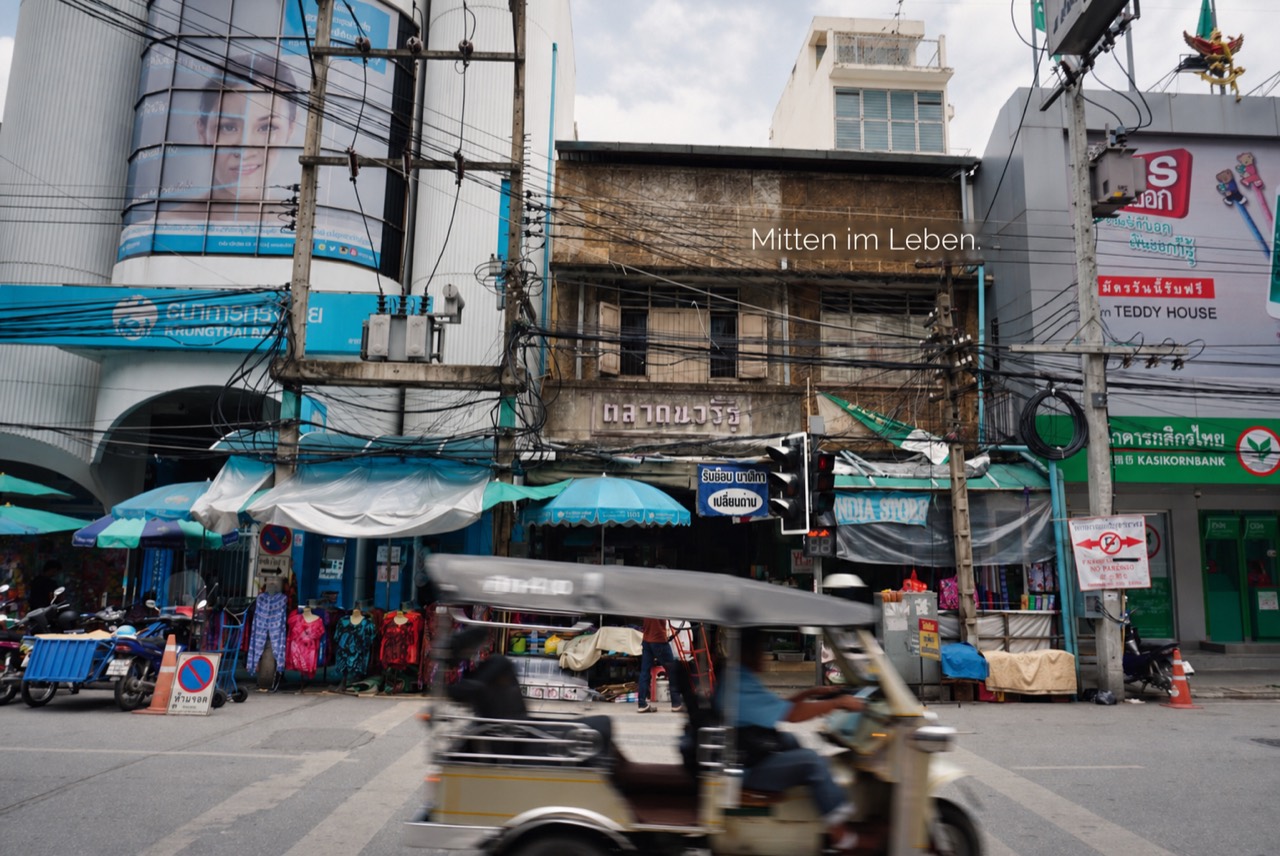 Straßenszene am Warorot-Markt in Chiang Mai mit vorbeifahrendem Tuk-Tuk